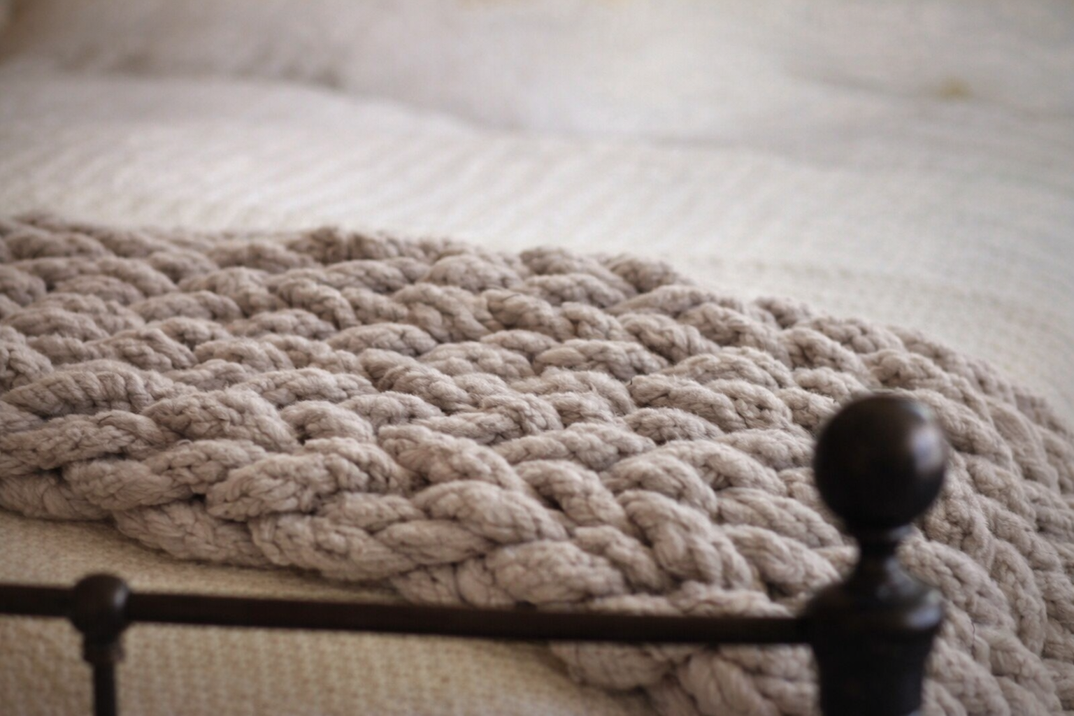 Taupe chunky chenille knit blanket 60x80 styled on neutral bed styling. taupe knitted blanket on a black metal bed frame
